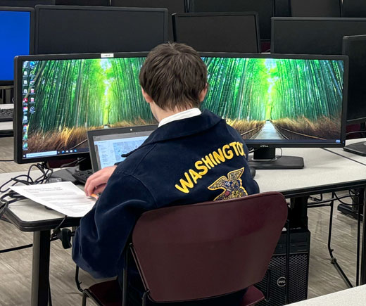 FFA student sitting at computer monitors.