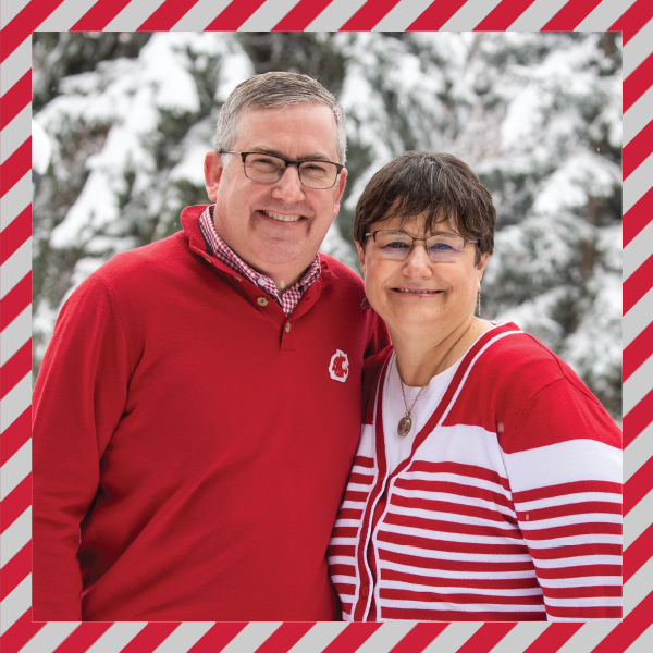 WSU President Kirk and First Lady Noel Schulz standing in front of snow-covered trees.