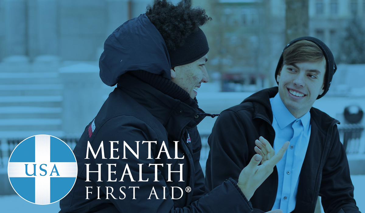 Mental Health First Aid logo and two students talking to one another.