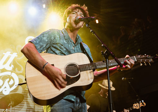 Wyatt Flores playing guitar and singing on stage.